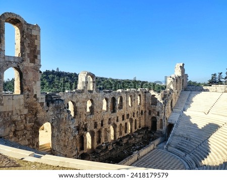 Photo of the Odeon of Herodes Atticus, a stone Roman theatre structure located on the southwest slope of the Acropolis of Athens, Greece. In the distance the Philopapos monument can be seen. Royalty-Free Stock Photo #2418179579