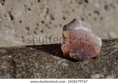 Rough chalcedony on natural wood.Macro shot of silica mineral on day light.Isolated scarlet brown stone on grayish background.Geology, mineralogy. Royalty-Free Stock Photo #2418179767
