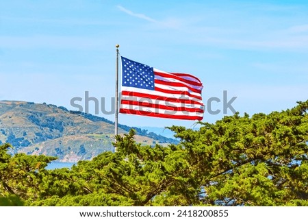 American flag flying on the wind, nature background wit mountains and trees. American Flag Overlooking Mountains American Flag on a hill overlooking trees and mountains. American flag in San Francisco
