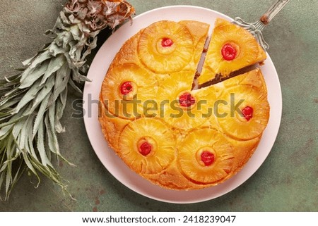 Homemade pineapple upside down pie with candied cherries . Tropical dessert on green background. Top view Royalty-Free Stock Photo #2418239047