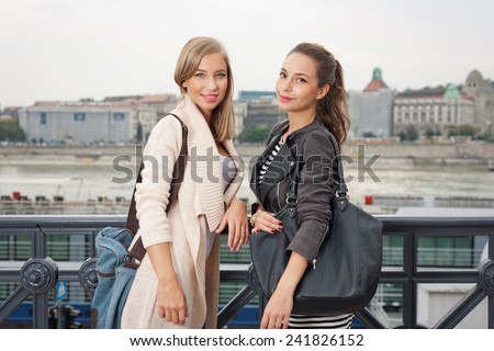 Outdoors portrait of two fashionable attractive student girls.