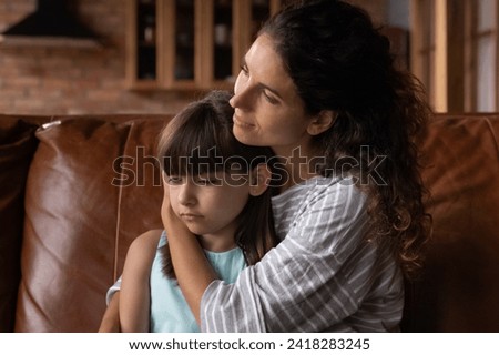 Caring latin foster mother cuddle preteen girl adopted child suffering from bullying misunderstanding at school talking consoling helping overcome troubles. Supportive parent hug stressed offended kid Royalty-Free Stock Photo #2418283245