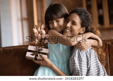 I love you so much mommy. Grateful latin foster mum stepmother embrace little adopted daughter get greeting on Women Day take tulips present. Excited adult sister thank younger one for birthday gift Royalty-Free Stock Photo #2418283297