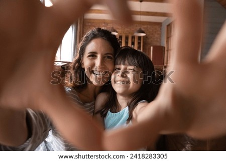 We love you. Latin mom and preteen daughter video bloggers influencers shoot content unite fingers in heart sign grateful for attention. Bonding mother and kid shoot selfie look at camera express love