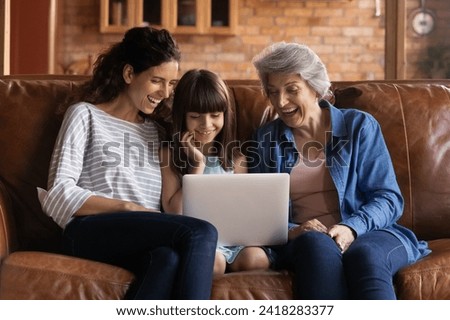 Funny cartoon. Happy intergenerational hispanic family of older grandmother adult mommy and preteen girl daughter grandchild spend free time on couch laugh enjoy cute video movie on laptop computer