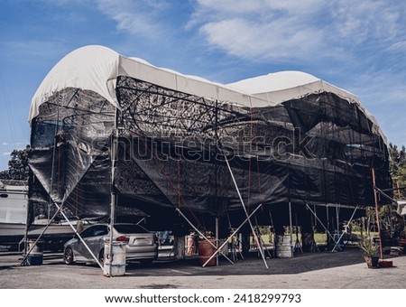 Motor yacht moored for repairs and service in dry dock Royalty-Free Stock Photo #2418299793