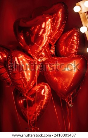 Extravagant glamour background with red foil heart air balloons for love party. Beautiful romantic burlesque room place for st valentines holiday illuminated vanity makeup mirror muffled light Royalty-Free Stock Photo #2418303437