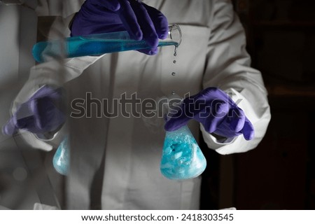 Smoky experiments with blue droplets. Scientist working on chemical reaction, generating thick smoke from a glass flask. Copyspace