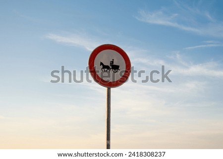 No entry for animal-drawn vehicles traffic sign, isolated sunset sky.
