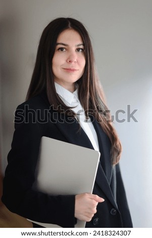 business portrait of a girl in a white shirt and black suit with a laptop. High quality photo