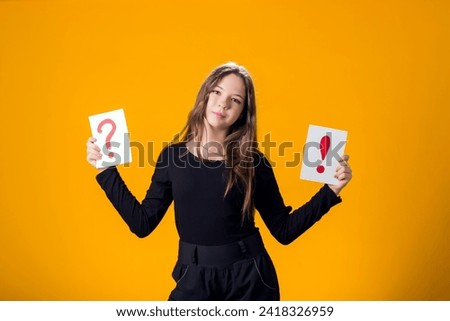 A portrain of kid girl holding cards with question mark and exclamation point. Children, idea and knowledge concept
