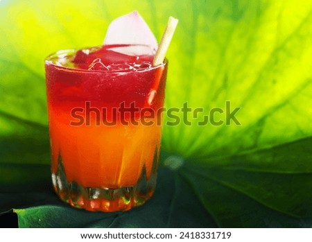Glass of cold passion fruit and roselle juice decorate with lotus petal against lotus leaf