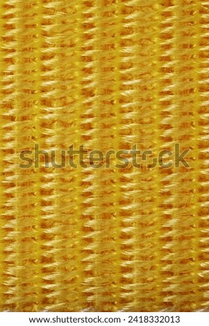 Yellow nylon braided threads fabric texture as background. Vertical photo.