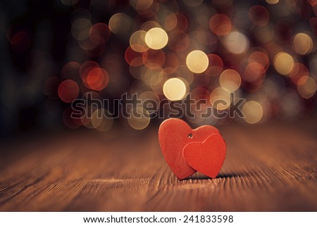 Close up of two red hearts on old wooden board against defocused lights