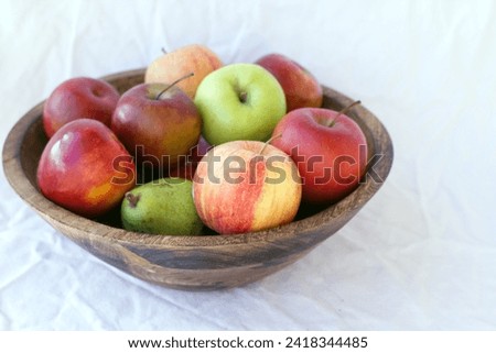 A teak bowl of homegrown apples and pears. Fruit concept.