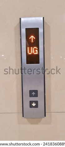 The push button for going up and down the elevator is usually located on the side wall of the elevator door. The sign is showing the direction up and the elevator is on floor UG.
