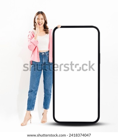 Cheerful beautiful Asian woman stand near big smartphone mockup of blank screen on white background. Royalty-Free Stock Photo #2418374047