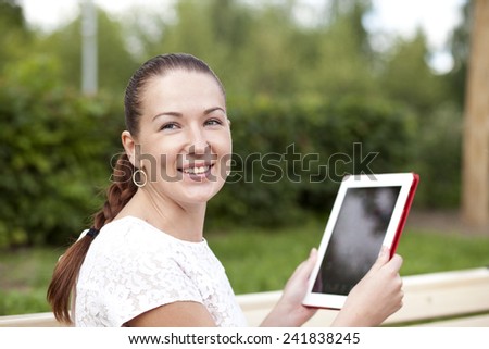 Young woman using a tablet computer on a park bench 