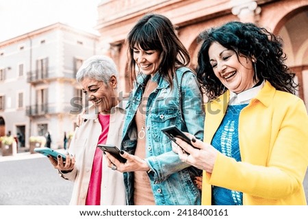 Happy senior women friends smile look read browse smartphone urban outdoors - Retired people having fun together with mobile phone - Positive elderly lifestyle concept with technology