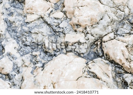 Glossy natural stone, untreated. Background, wallpaper. Beautiful background made of untreated wild stone. Close-up where the texture of the stone is clearly visible.