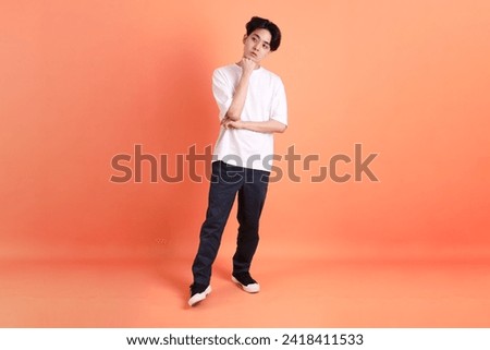 The Adult east Asian man with braces standing on the pink or orange background.