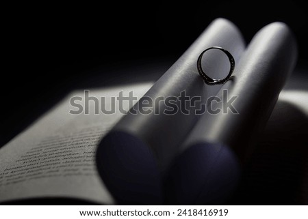 Selective focus on the ring on the open book results in a heart-shaped shadow. Romantic. A symbol of love.