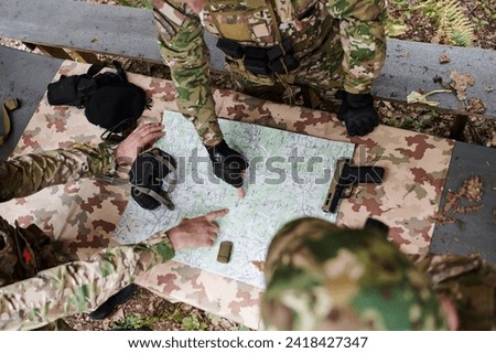 A highly trained military unit strategizes and organizes a tactical mission while studying a military map during a briefing session Royalty-Free Stock Photo #2418427347