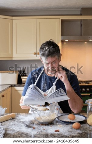 Cookery lessons. A humorous picture of a man reading a cookery book with a confused look on his face as attempts to cook or prepare food.