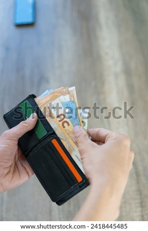 photograph of hands removing euro banknotes from a wallet with cards