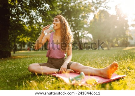 Young woman practicing yoga during workout in park. Fitness. Active lifestyle. Royalty-Free Stock Photo #2418446611
