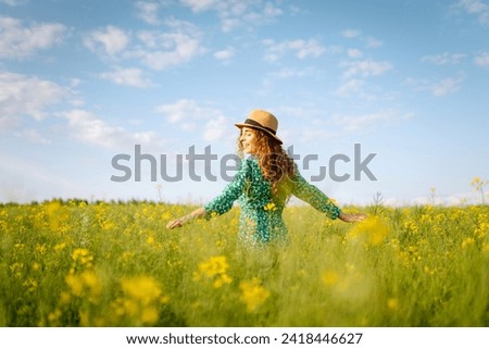 Beautiful woman walking flowering field gently touch yellow flowers. Nature, fashion,  summer lifestyle. 
