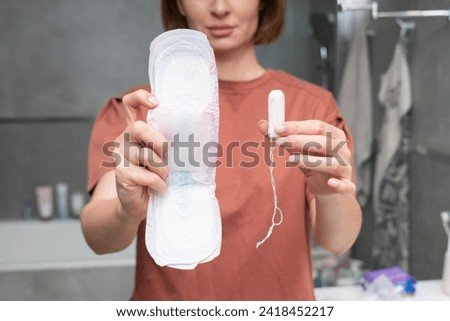 In a thoughtful moment, a woman contemplates her choice between pads and tampons, considering the comfort and convenience of each option Royalty-Free Stock Photo #2418452217