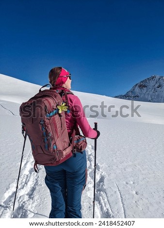 young woman enjoys the beautiful snowy mountain landscape on a ski route. Ski mountaineering in Switzerland. High quality photo