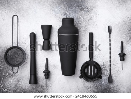 Black matt steel shaker,pourer,spoon,strainer,muddler and jigger on light board. Royalty-Free Stock Photo #2418460655