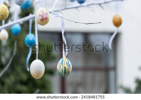 Colorful handmade egges for easter in branches outdoor. Decorating trees with hanging eastereggs in city street. Tradition holiday on christianity religion. Symbol of resurrection to new life. Royalty-Free Stock Photo #2418481755