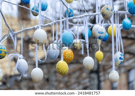 Colorful handmade egges for easter in branches outdoor. Decorating trees with hanging eastereggs in city street. Tradition holiday on christianity religion. Symbol of resurrection to new life. Royalty-Free Stock Photo #2418481757