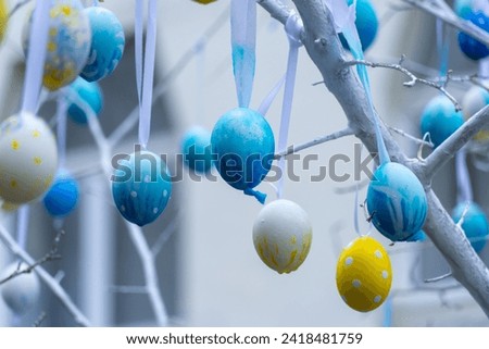 Colorful handmade egges for easter in branches outdoor. Decorating trees with hanging eastereggs in city street. Tradition holiday on christianity religion. Symbol of resurrection to new life. Royalty-Free Stock Photo #2418481759