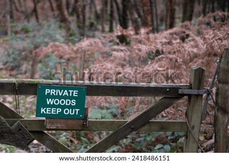 Wooden gate with sign on warning of private woods in middle of forest, East Sussex, England