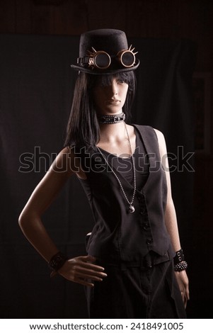 Plastic woman mannequin wearing steampunk clothes and accessories posing on a black background with a split lighting effect