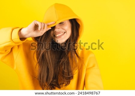 Close up photo of trendy cheerful cute nice sweet youngster laughing looking away toothy wearing hood isolated over yellow color background. Funny girl look playful holding hood. Royalty-Free Stock Photo #2418498767