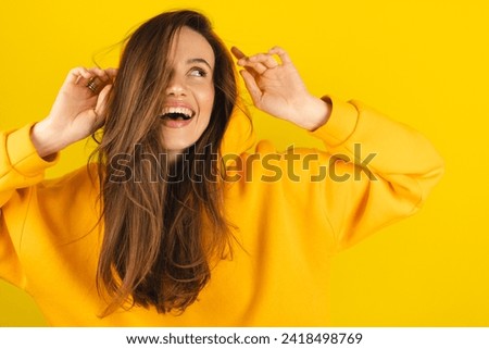 Close up photo of trendy cheerful cute nice sweet youngster laughing looking away toothy wearing hood isolated over yellow color background. Funny girl look playful holding hood. Royalty-Free Stock Photo #2418498769