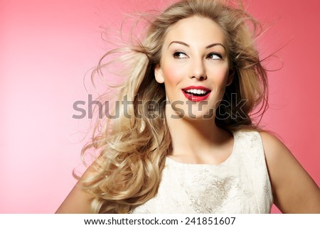 Beautiful woman with long blond hair and nice makeup posing on pink background.  