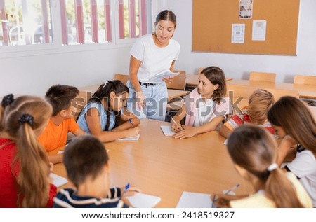 Schoolchildren and teacher brainstorming round table in school classroom