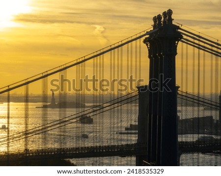 Aerial view of the Manhattan Bridge spanning the East River with the Statue of Liberty in the backdrop on a clear day.
