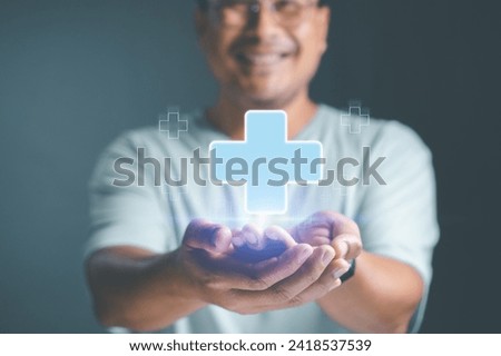 Mental health care mental rejuvenation concept. Man smiling good mood hand holding virtual blue plus sign for positive thinking mindset or healthcare insurance symbol. Royalty-Free Stock Photo #2418537539