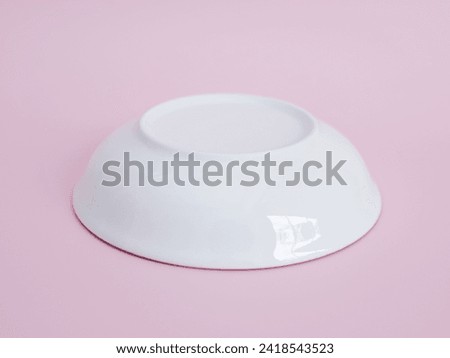upside down white porcelain bowl on pink background. Minimal style. Royalty-Free Stock Photo #2418543523