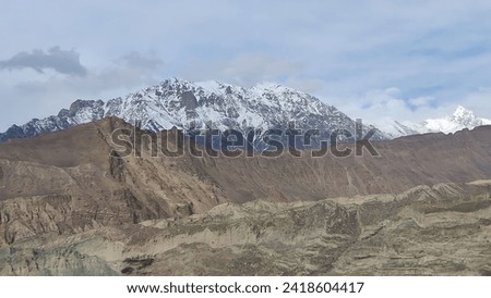 A snow-capped mountain range in the distance, with a valley in the foreground. 