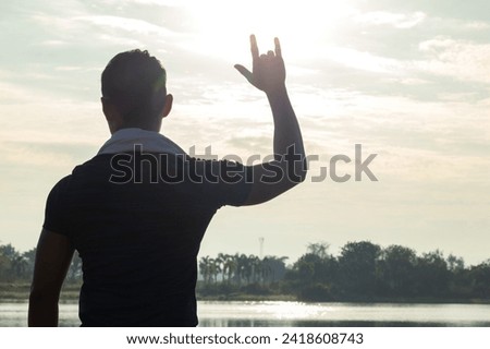 young man raises his hand and makes sign language symbol of "I love you" show love and friendship for each other. Sign language is also universal language that can be easily understood as saying love.