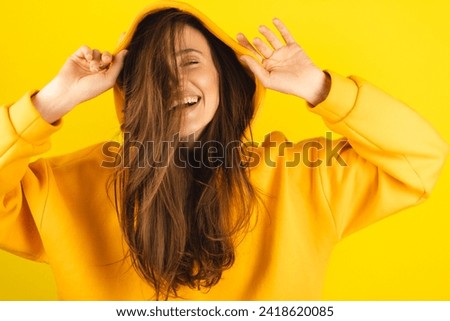 Close up photo of trendy cheerful cute nice sweet youngster laughing looking away toothy wearing hood isolated over yellow color background. Funny girl look playful holding hood. Royalty-Free Stock Photo #2418620085