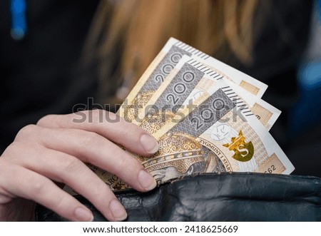 Woman hides money in her wallet, Polish cash Royalty-Free Stock Photo #2418625669